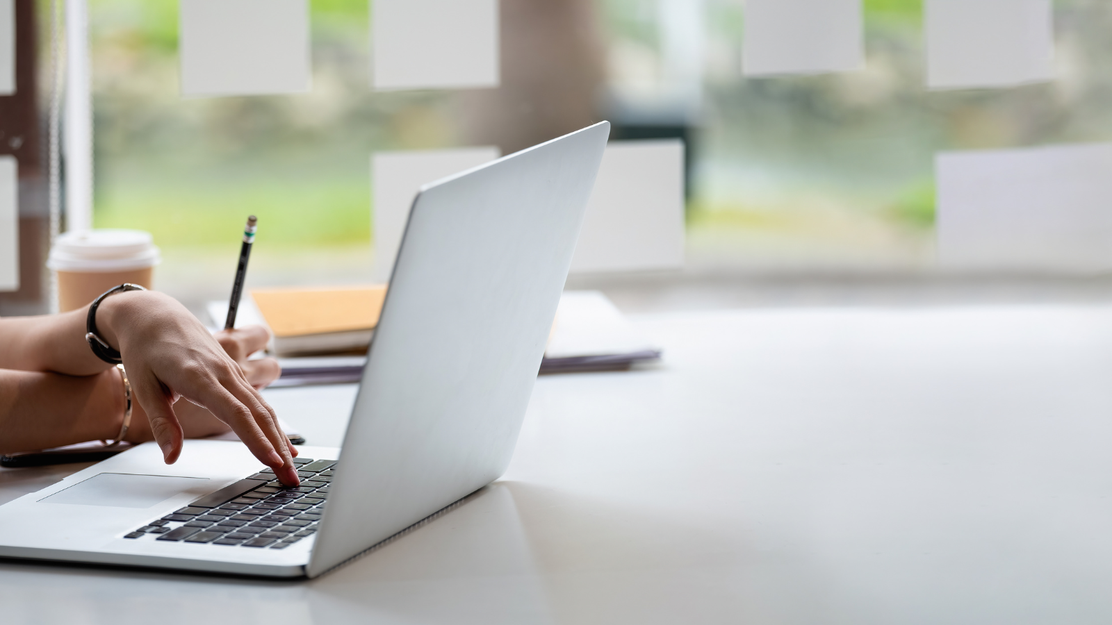 A hand typing on a laptop with a blurred background